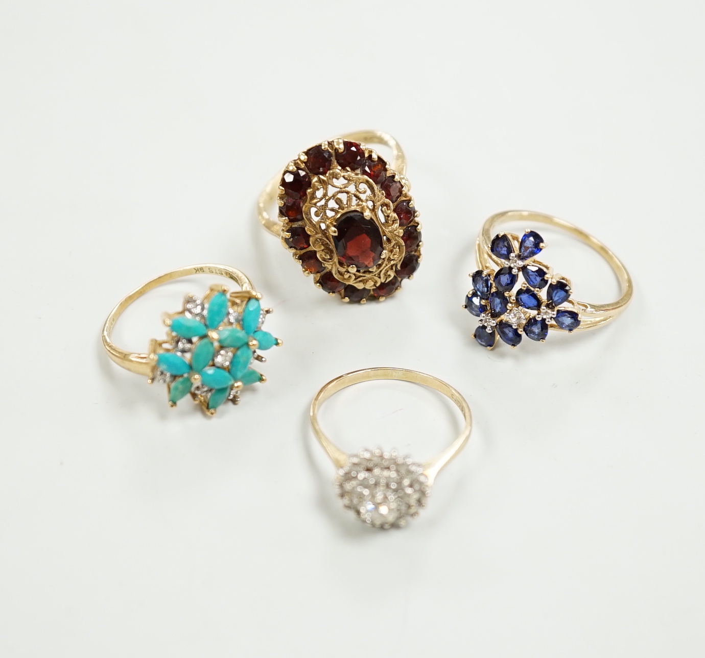 Four assorted modern 9ct gold and gem set dress rings including diamond cluster and garnet cluster, gross weight 13.6 grams.